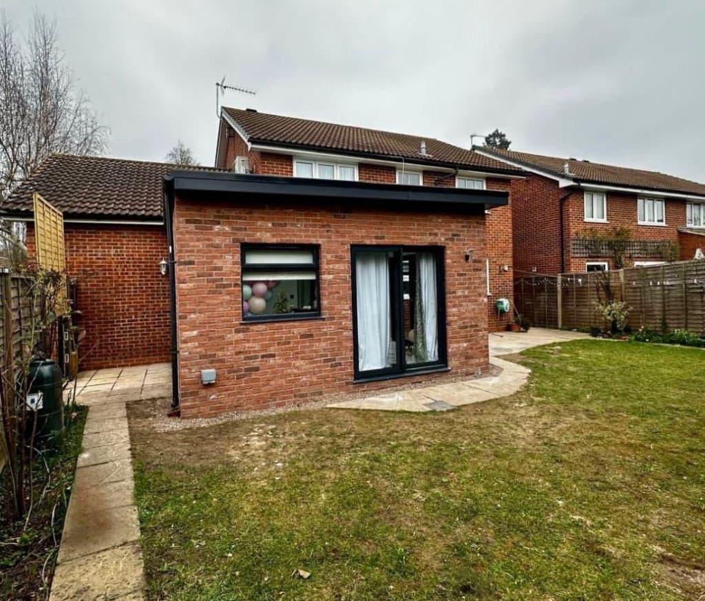 Red brick home extension under construction with full scaffolding