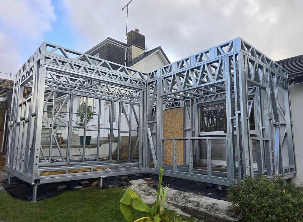 Steel frame rear extension under construction on a red brick house